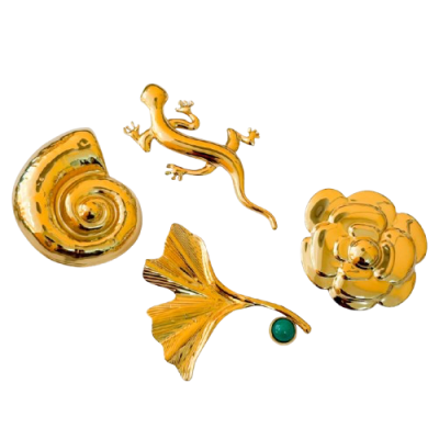 Quatro broches dourados com formas de concha, lagarto, folha e flor
