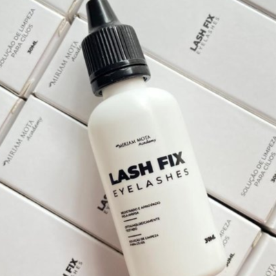 Frasco branco de solução para limpeza de cílios Lash Fix de 30ml com tampa preta e várias caixas brancas ao fundo.