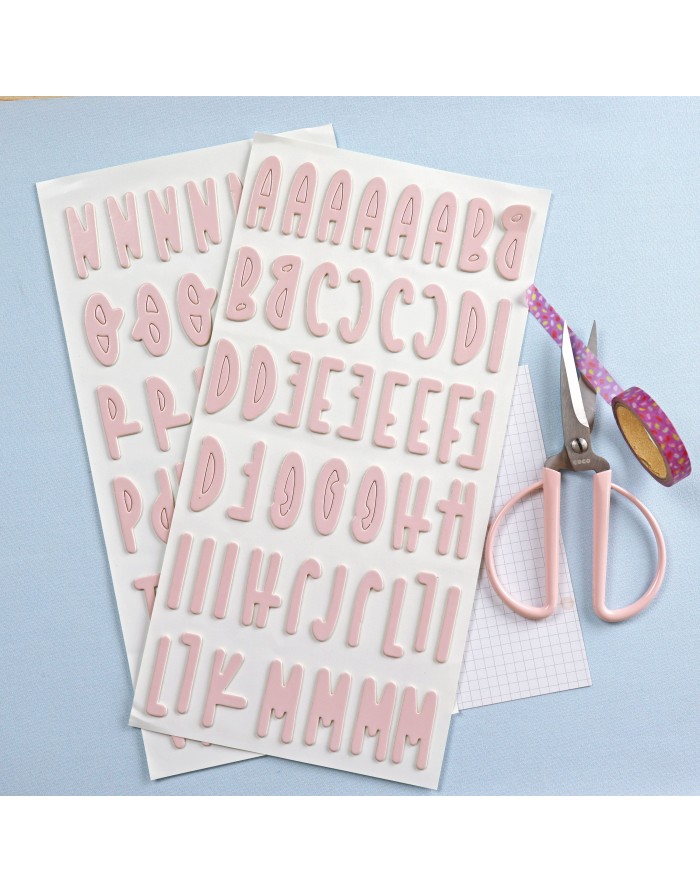 Conjuntos de autocolantes de letras cor-de-rosa, tesoura rosa, fita decorativa roxa e papel quadriculado sobre fundo azul