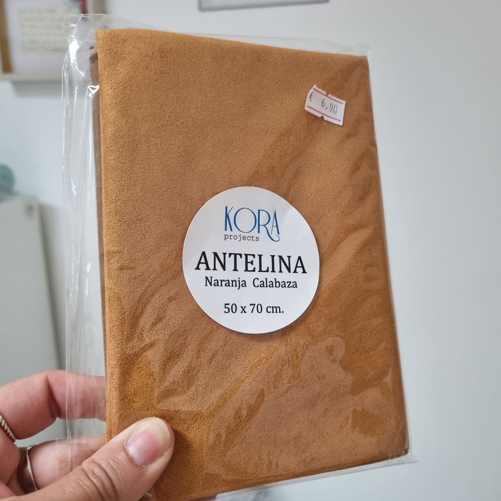 Bolsa em tecido cor de laranja claro com etiquetas, dentro de embalagem plástica