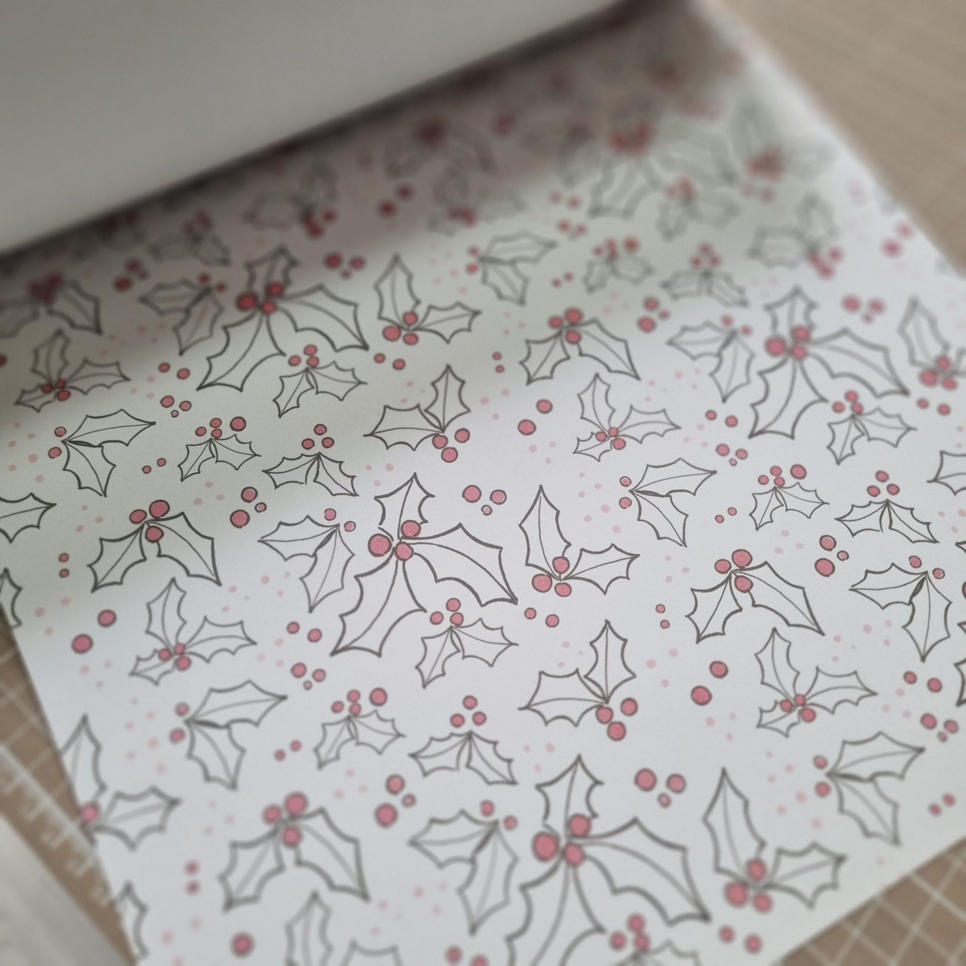 Papel de embrulho branco com padrão de folhas de azevinho e bagas vermelhas