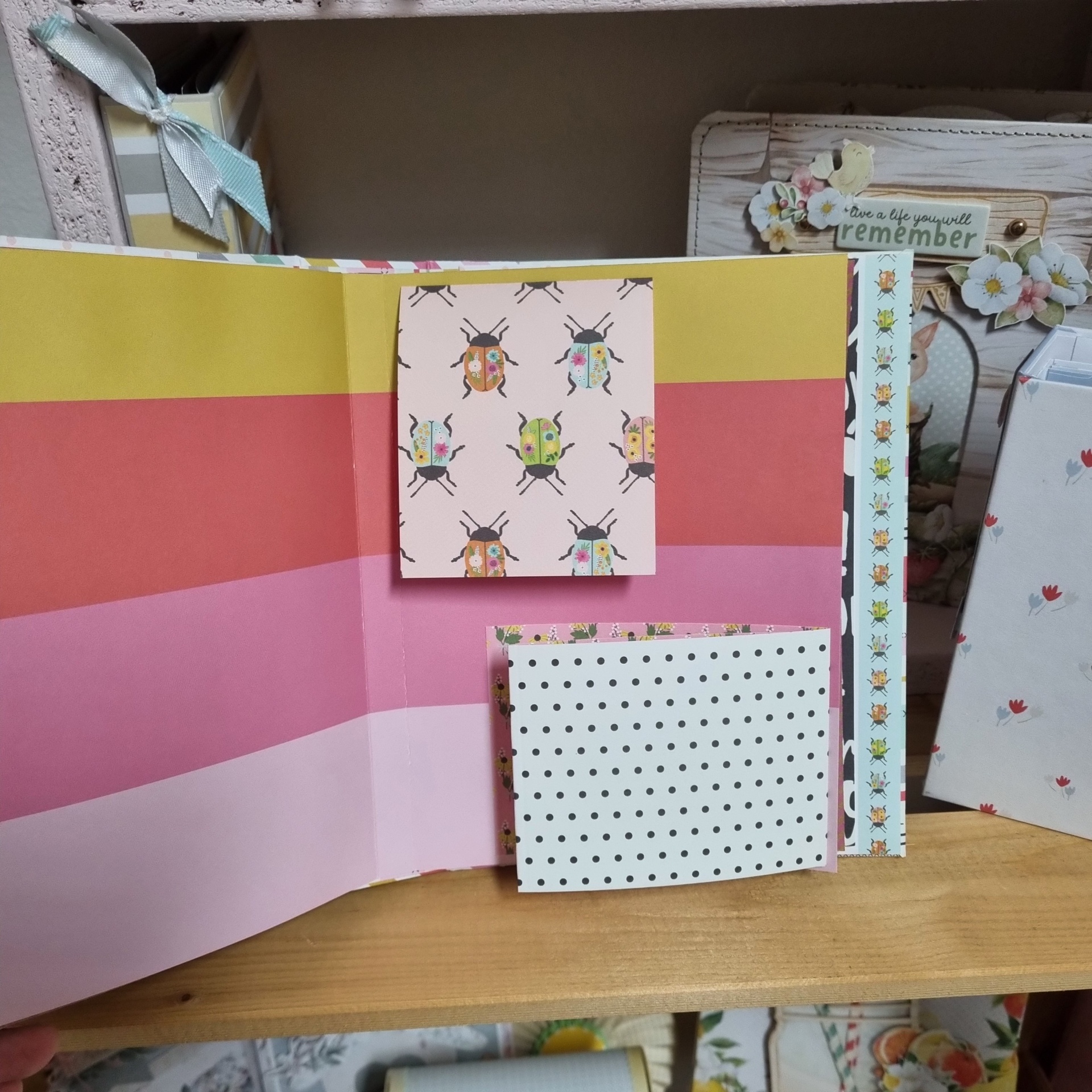 Livro decorativo aberto com páginas coloridas e padrões de joaninhas e bolinhas