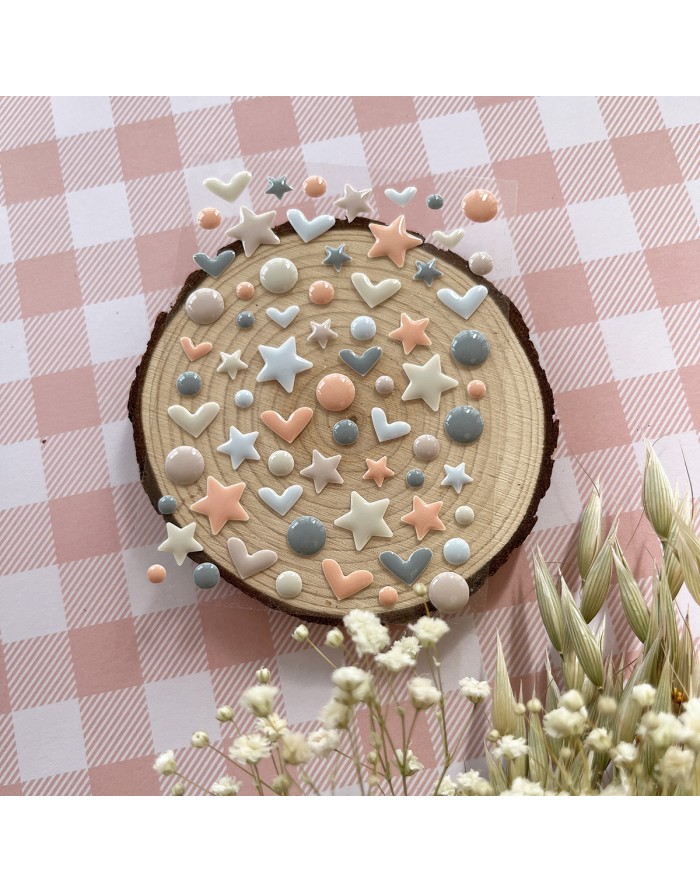 Adesivos coloridos em formato de estrelas e corações sobre disco de madeira com fundo xadrez rosa e branco