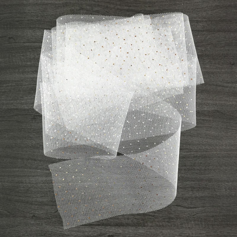 Lenço branco translúcido com pontos dourados sobre madeira escura