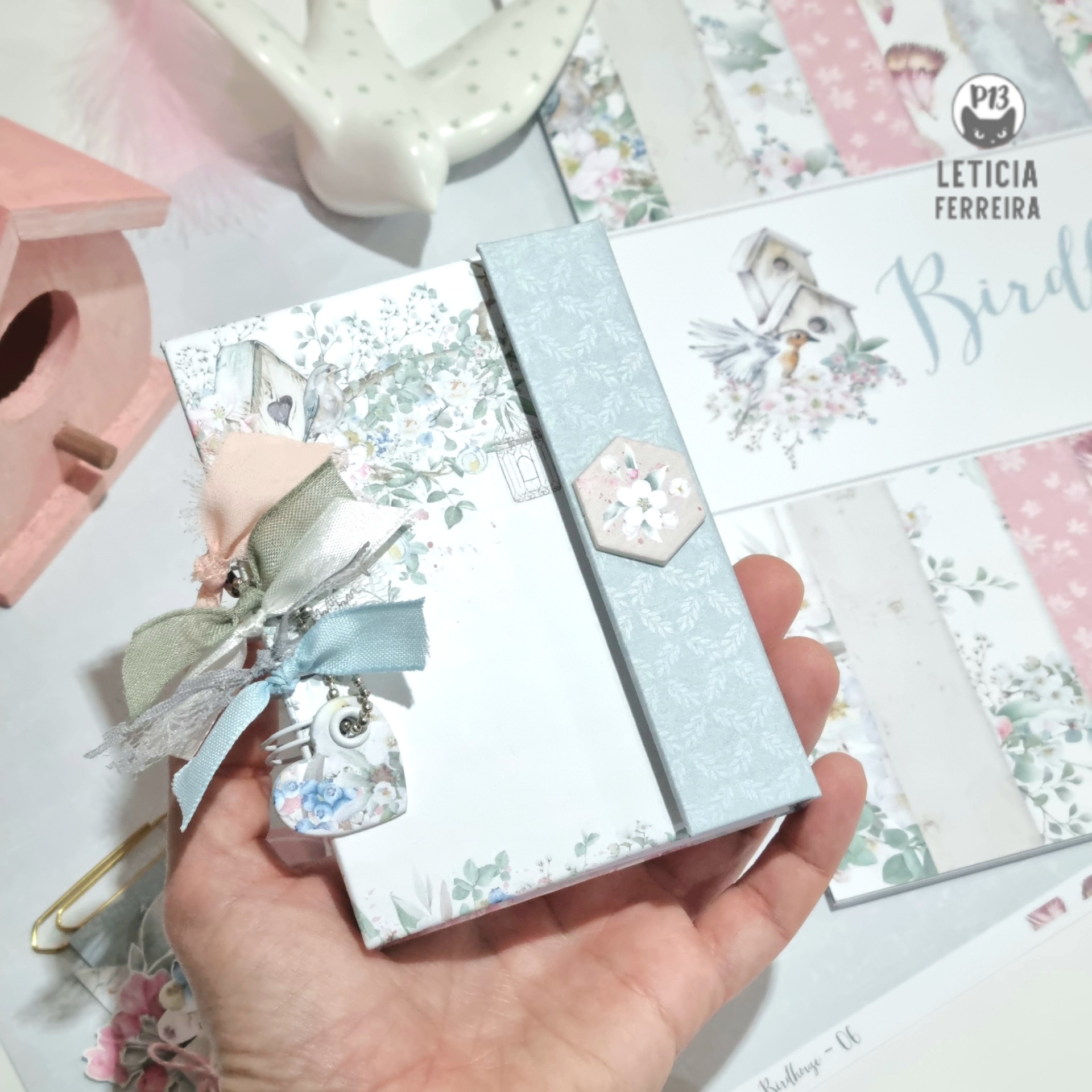 Pequeno álbum decorado com padrões florais pastel e chaveiro colorido