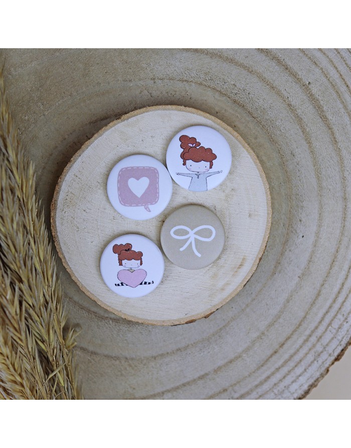 Quatro bottons redondos com desenhos sobre base de madeira clara