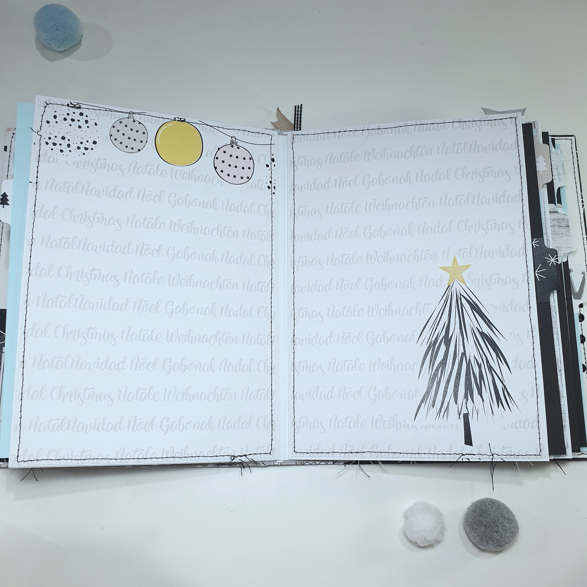 Livro aberto com decoração natalícia e bolas de lã coloridas no fundo branco