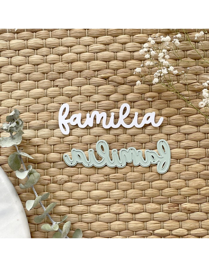 Duas palavras decorativas 'familia' em branco e azul claro sobre esteira de palha com folhas e flores secas