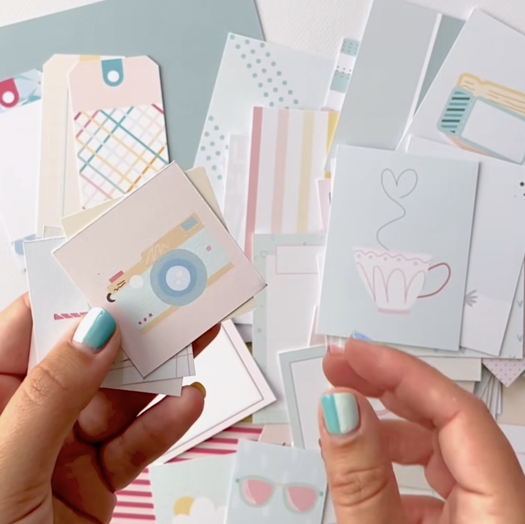 Pequenos cartões e etiquetas de papel coloridos em mãos com unhas verdes