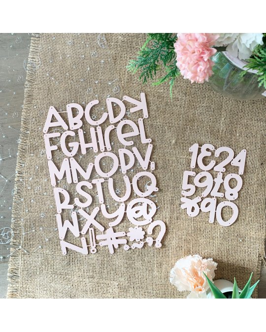 Letras e números recortados cor de rosa sobre tecido juta e flores