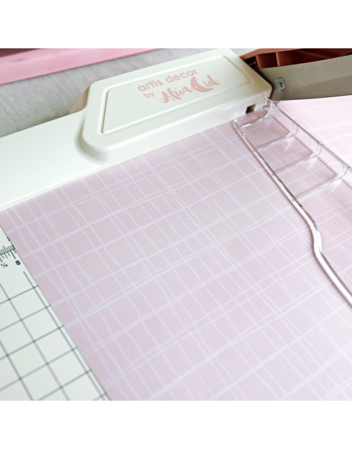 Tesoura de corte branca numa base de corte com papel rosa decorativo