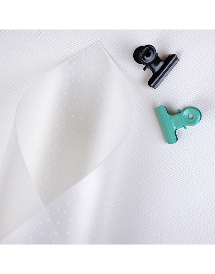 Folha branca com pontos transparentes e duas molas de metal preta e verde