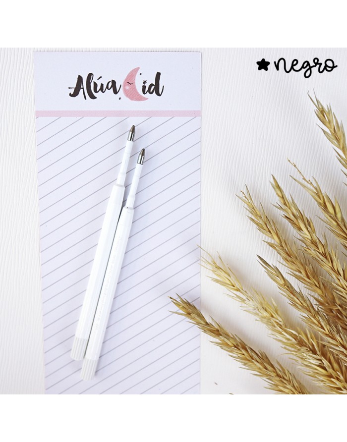 Duas canetas brancas sobre bloco de notas e ramos secos ao lado