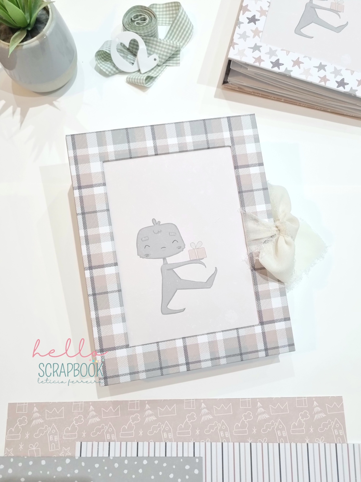 Livro scrapbook com capa xadrez bege e branca e personagem ilustrado segurando presente
