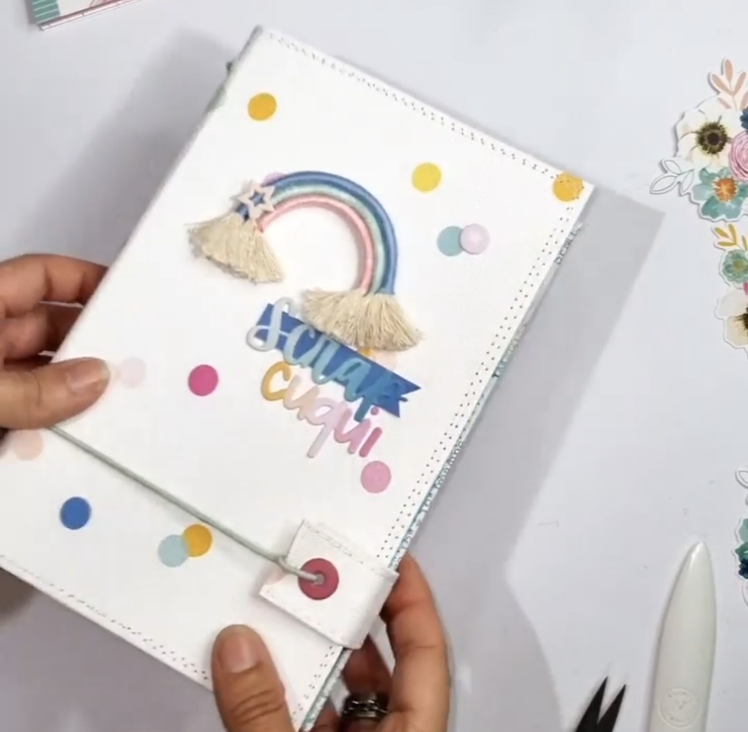 Capa de caderno branco com arco-íris e texto colorido