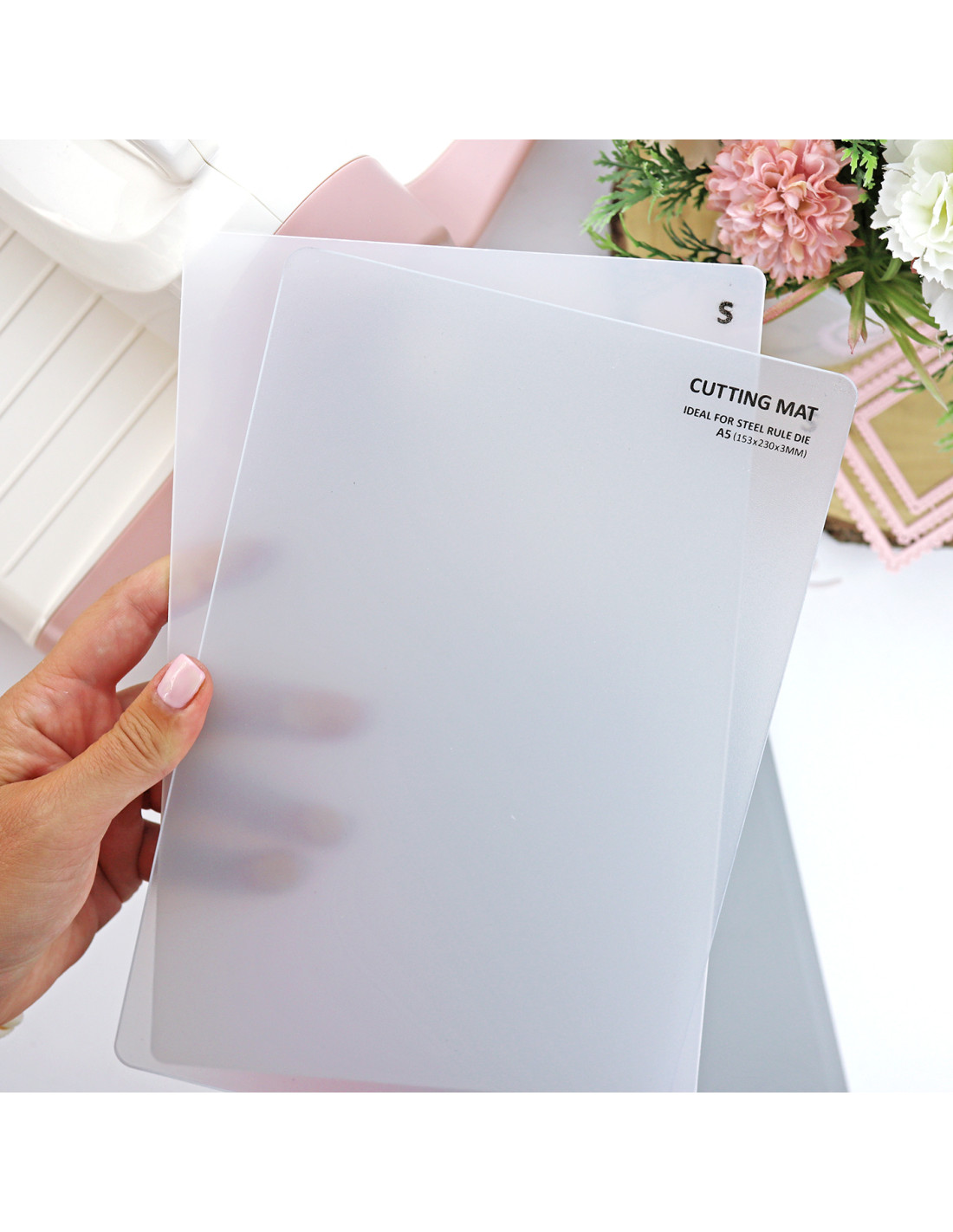 Bases de corte transparentes em plástico fosco com texto preto, seguradas por mão feminina