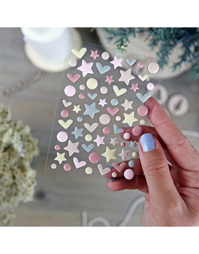 Folha de autocolantes coloridos segurada por mão feminina com unhas pintadas de azul claro