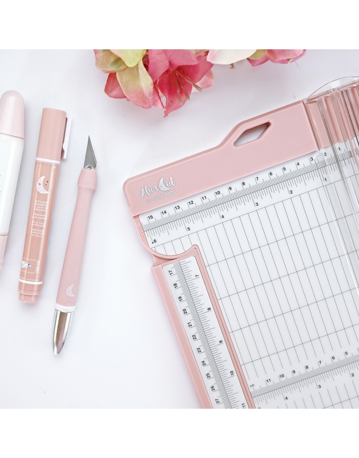 Material de escritório rosa e branco com canetas e cortador de papel em superfície branca com flores.