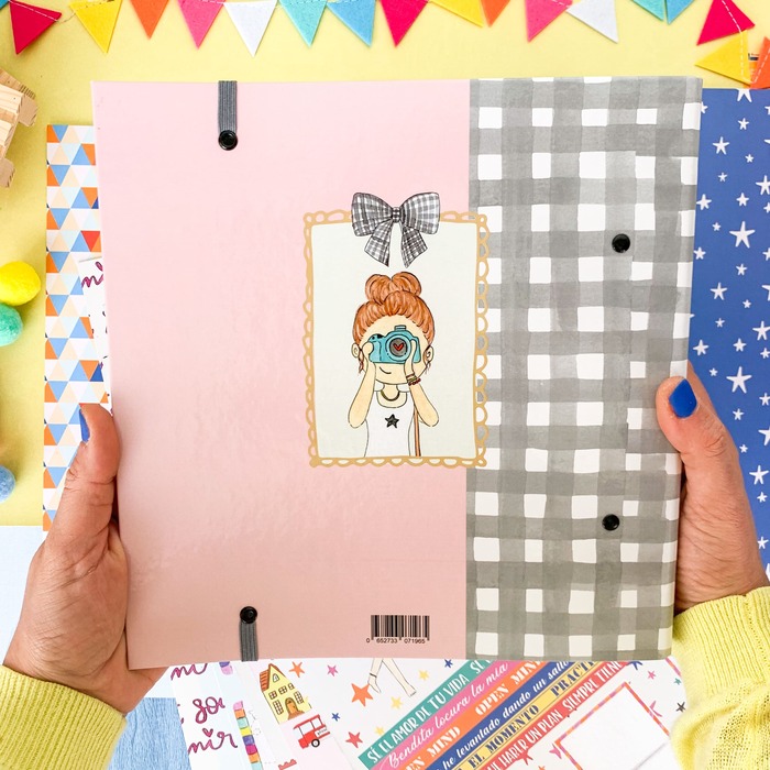 Capa de caderno rosa e cinzento com desenho de menina com câmara fotográfica e fundo colorido