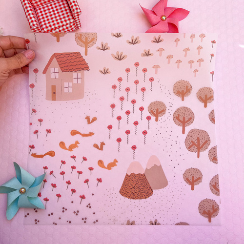 Guardanapo de papel com padrão de casa, árvores e montanhas em tons castanhos e rosa