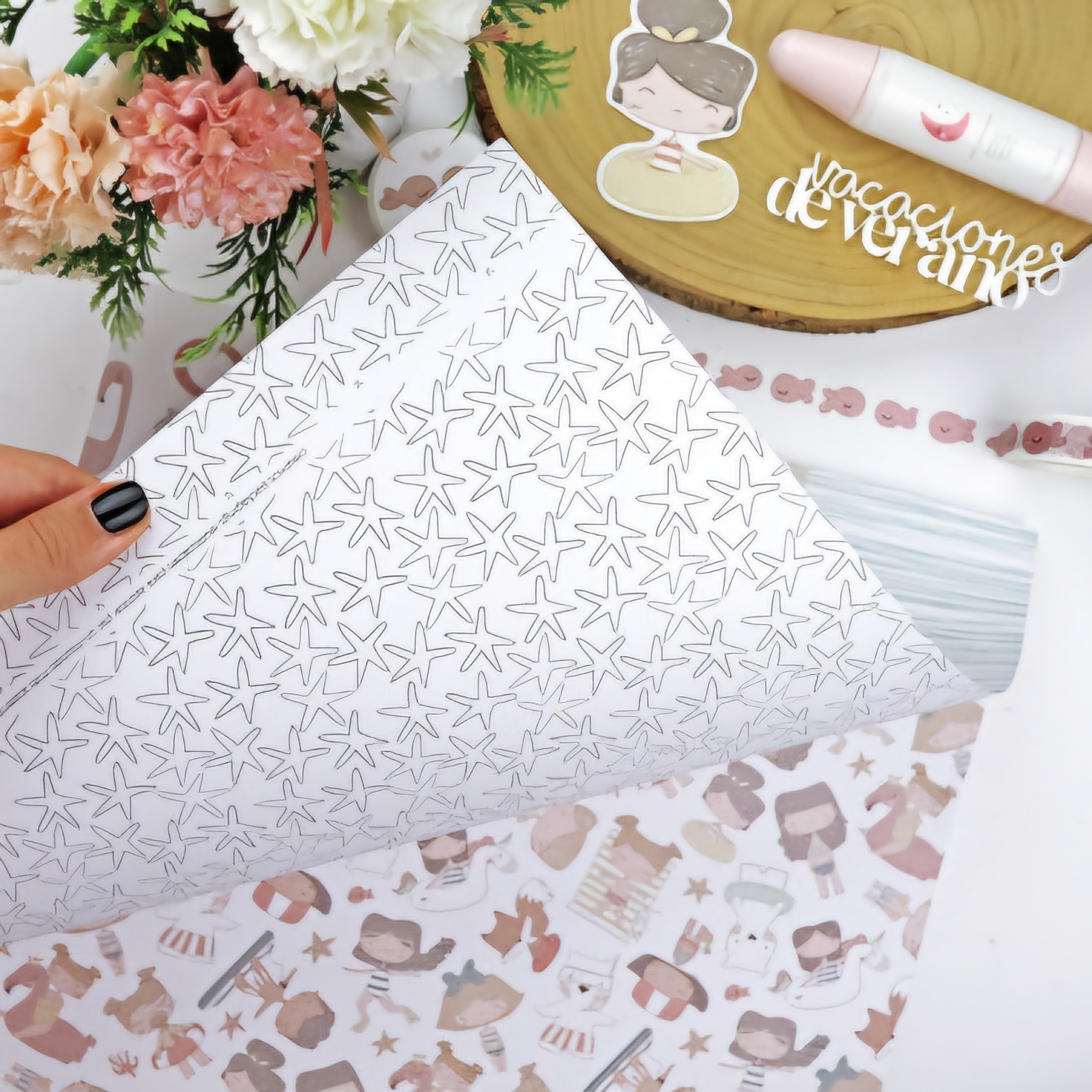 Papel decorativo dupla face com padrões de estrelas do mar e figuras femininas, flores e batom numa mesa