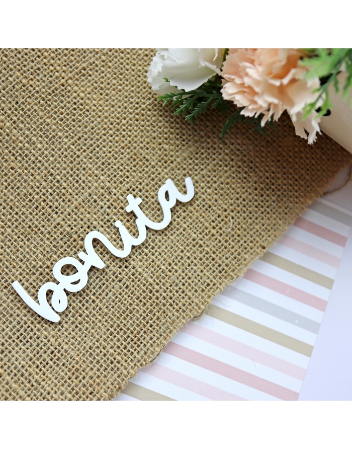 Palavra decorativa 'bonita' em madeira branca sobre juta com flores ao lado