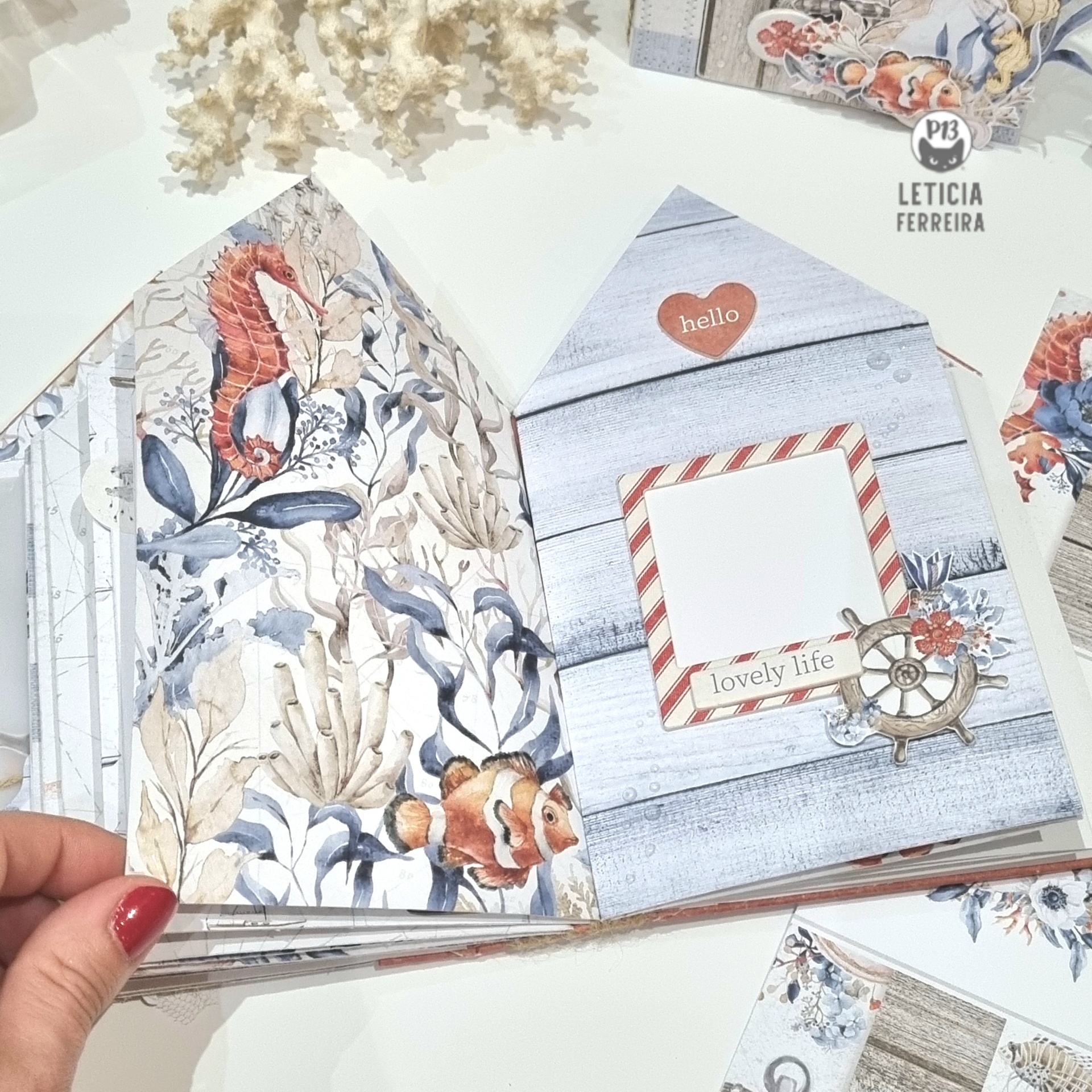 Livro artesanal em formato de casa com ilustrações marinhas e textos decorativos