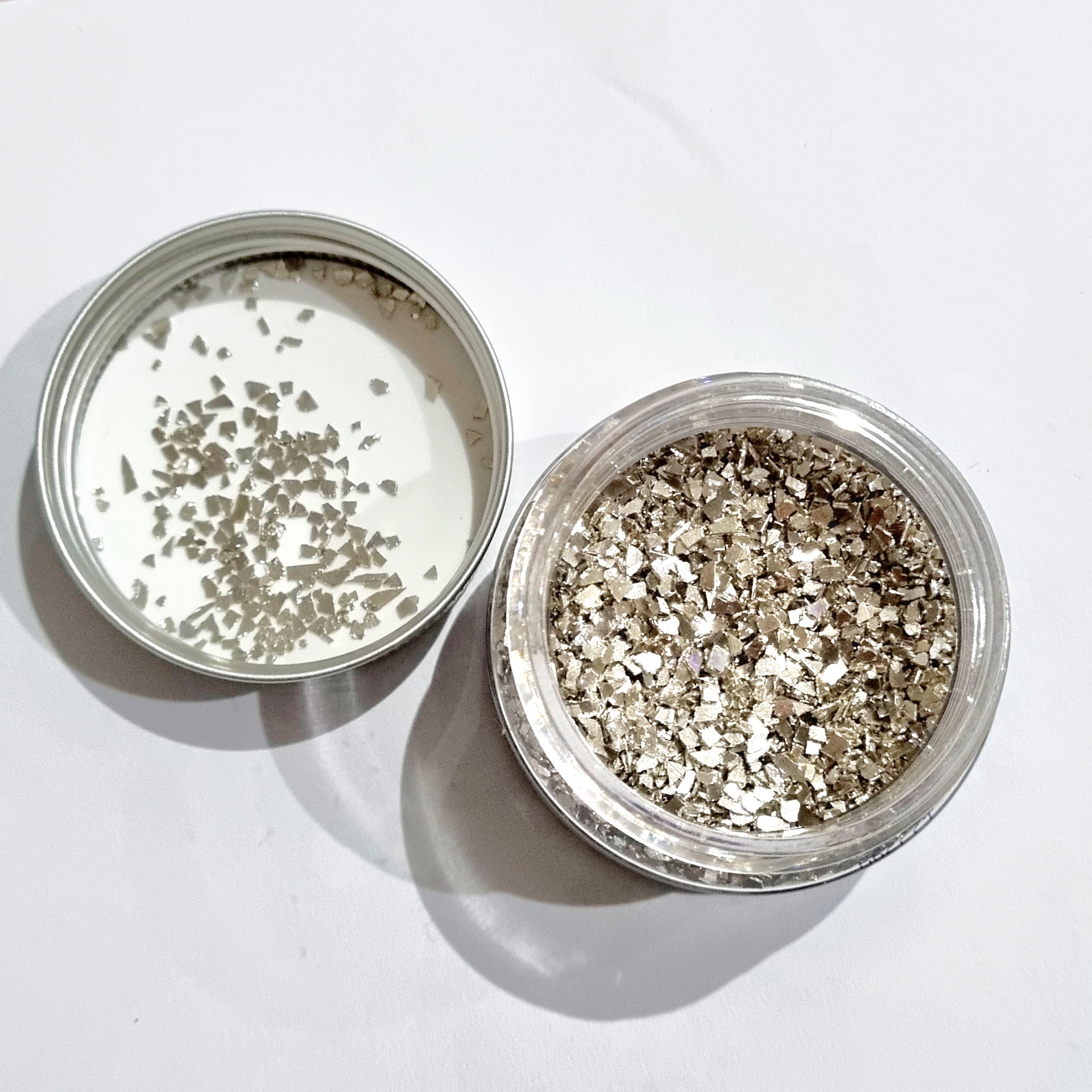 Frasco aberto com partículas prateadas brilhantes e tampa com partículas semelhantes