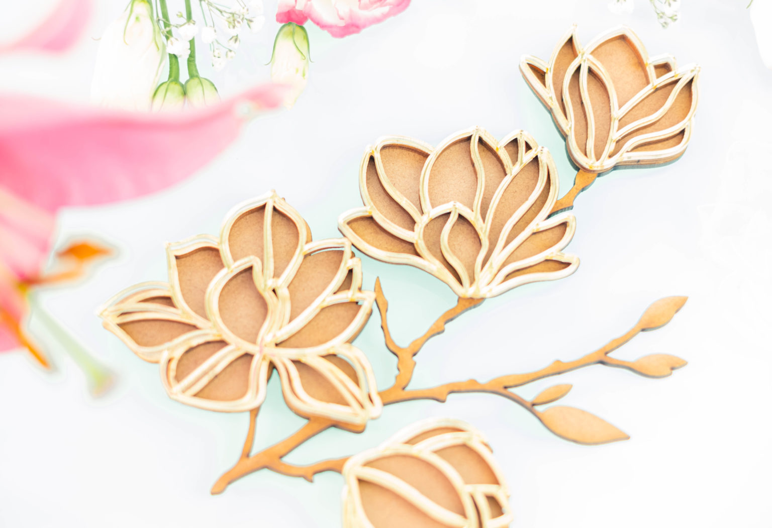 Ramo decorativo de flores bege e castanho em fundo branco com flores rosas desfocadas