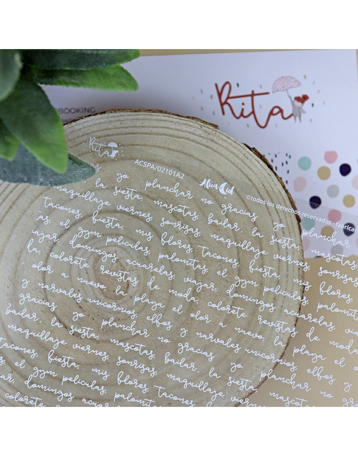 Lenço branco com padrões escritos em branco sobre suporte de madeira, planta verde e papel com logo Ritar