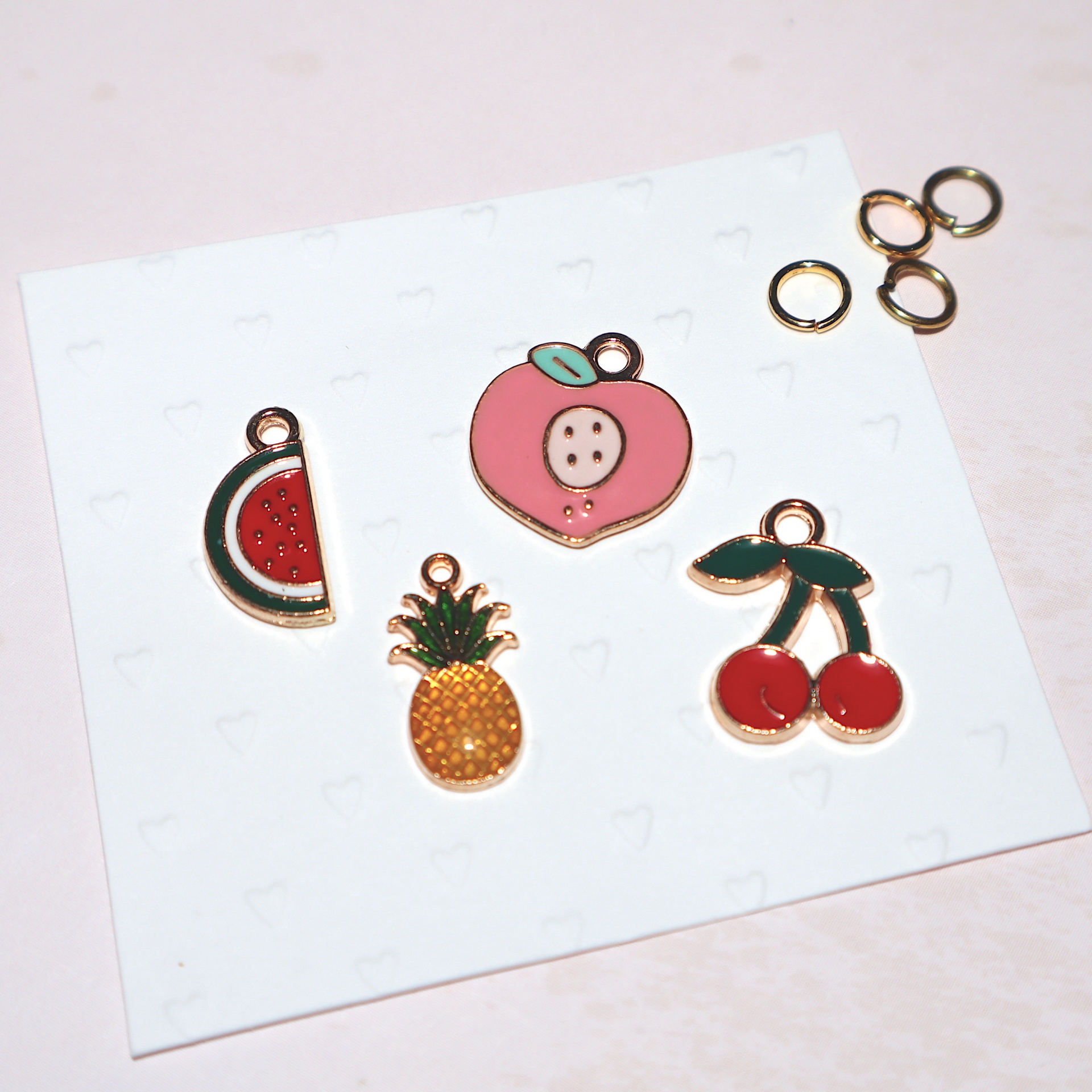 Pendentes coloridos em forma de frutas sobre cartão branco