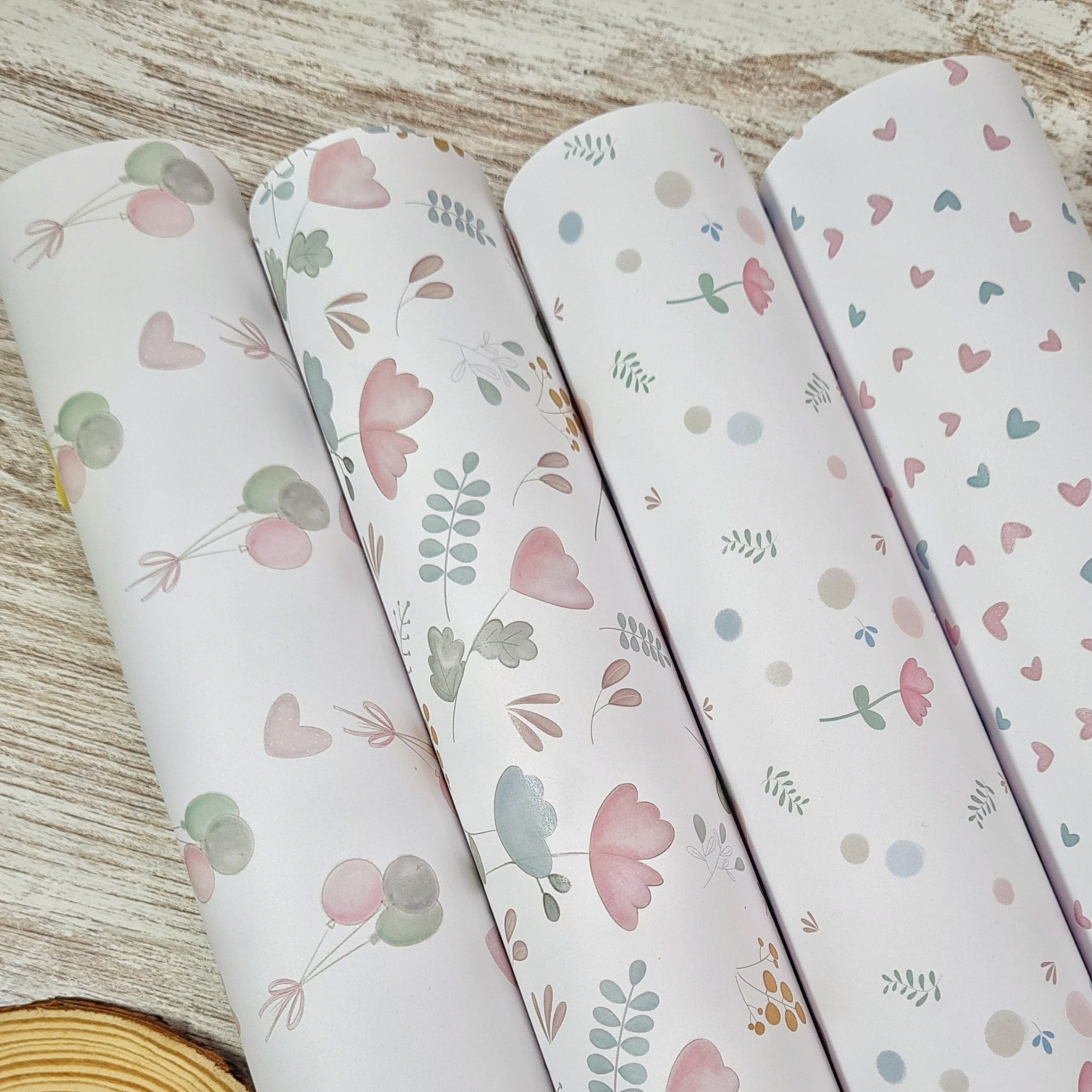 Quatro rolos de papel com diferentes padrões delicados num fundo branco