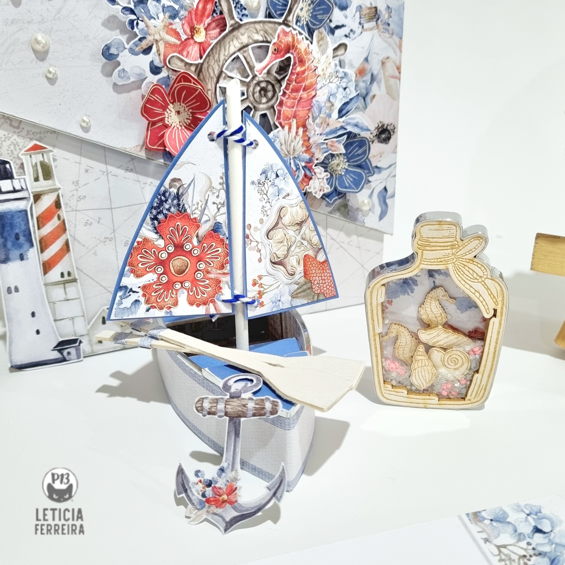 Barco decorativo de madeira azul, branco e vermelho com vela e frasco com conchas em mesa branca