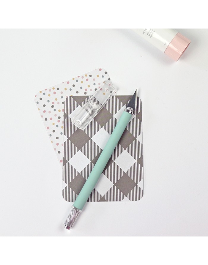 Cortador de unhas azul-claro sobre cartões decorados e tubo branco com tampa rosa