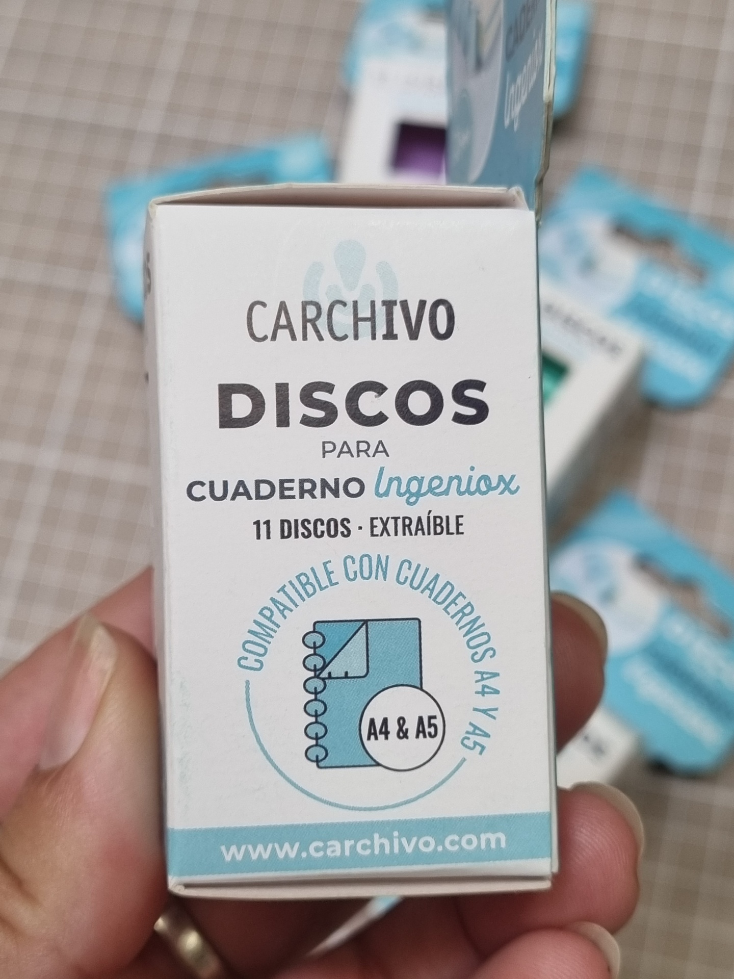 Caixa branca com texto e selo azul para discos de caderno