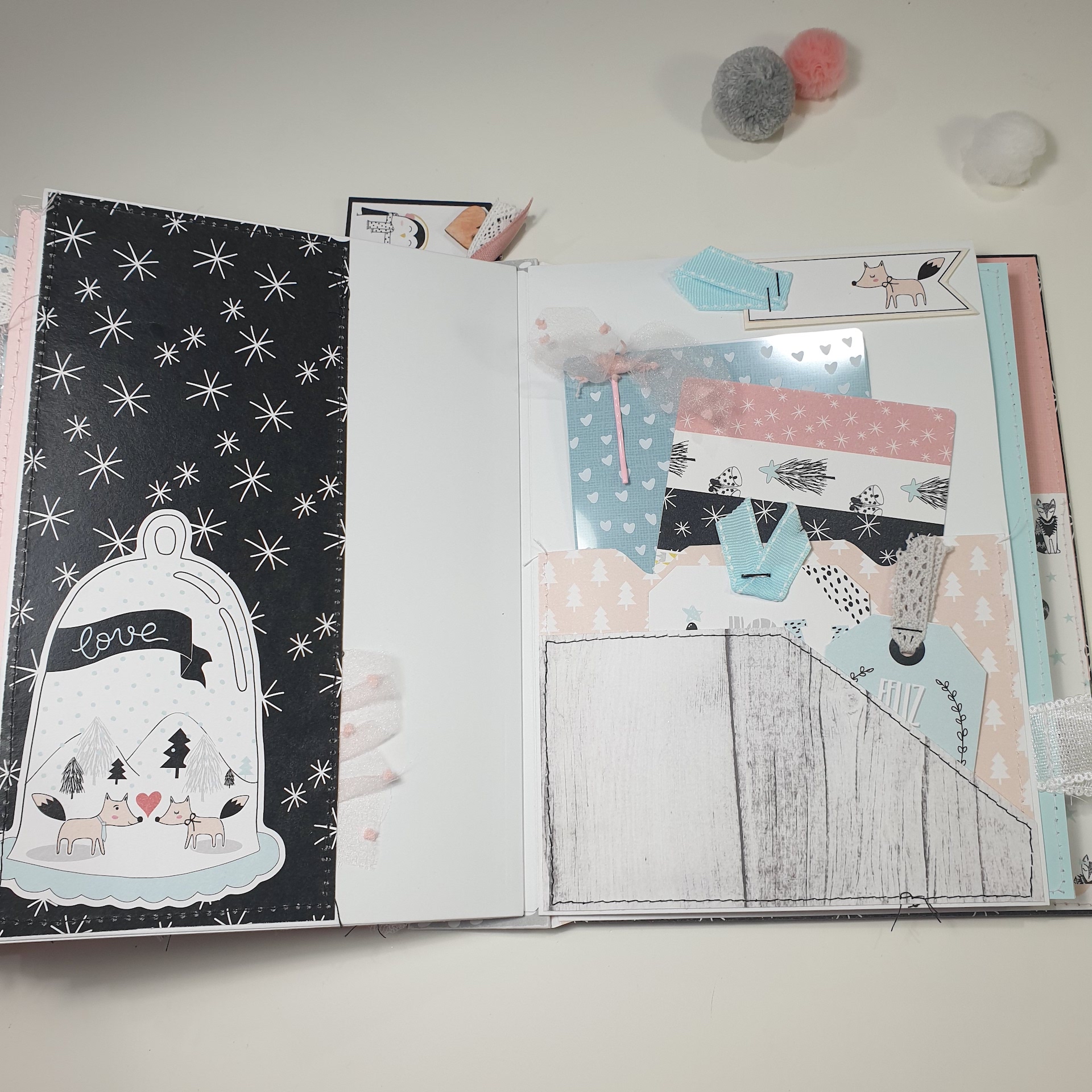 Livro ou álbum de papelaria aberto com ilustrações e padrões em tons pastéis e objetos decorativos ao fundo