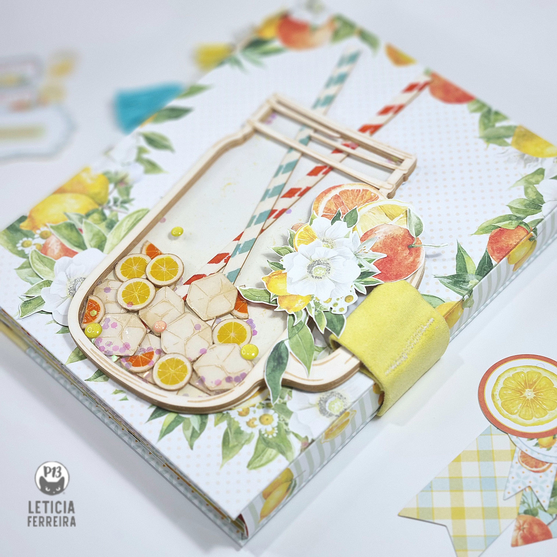 Caderno decorado com padrão floral e frutas cítricas, com recorte em forma de jarro e fecho amarelo.