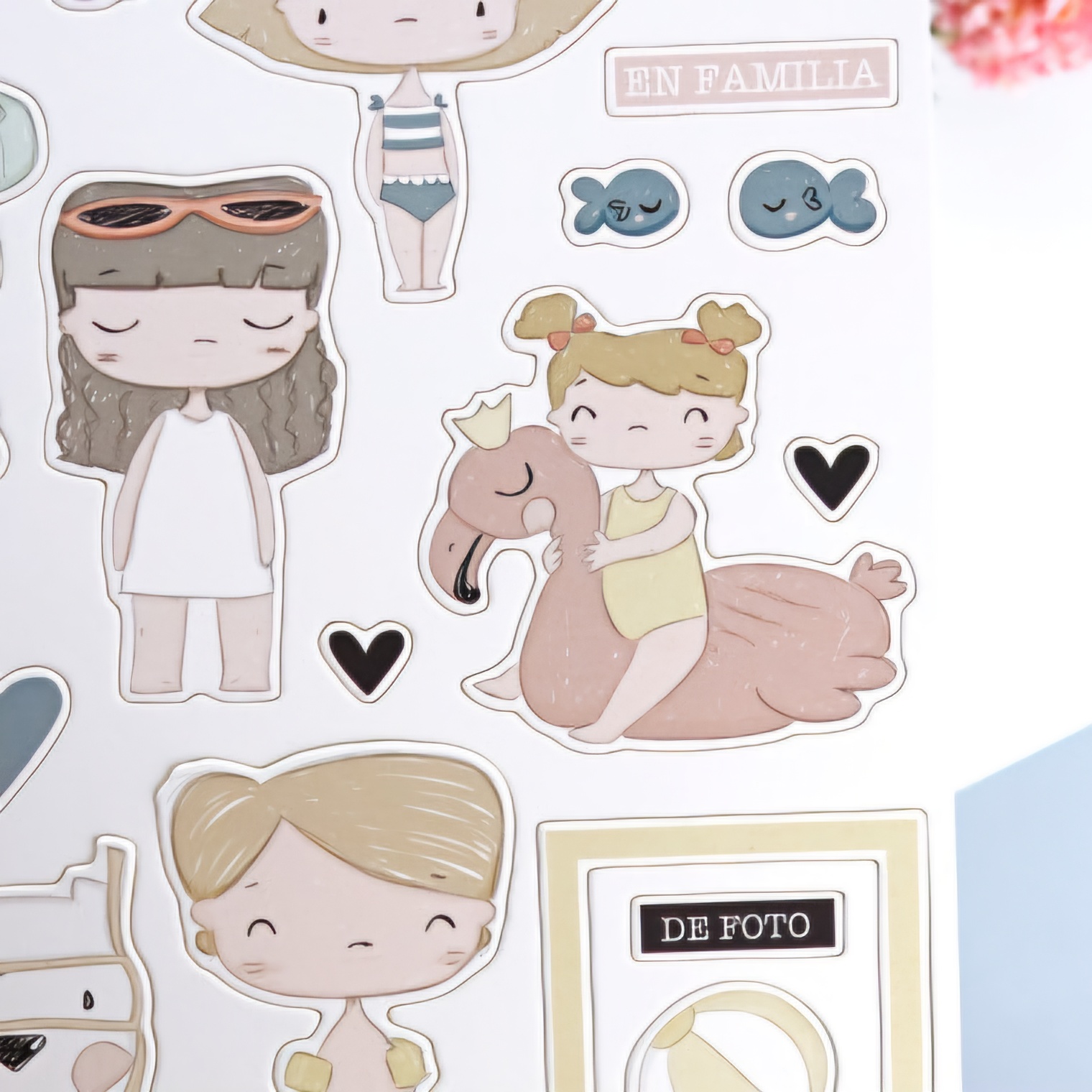 Folha de autocolantes com desenhos de crianças, um flamingo, peixes e texto em castanho claro.