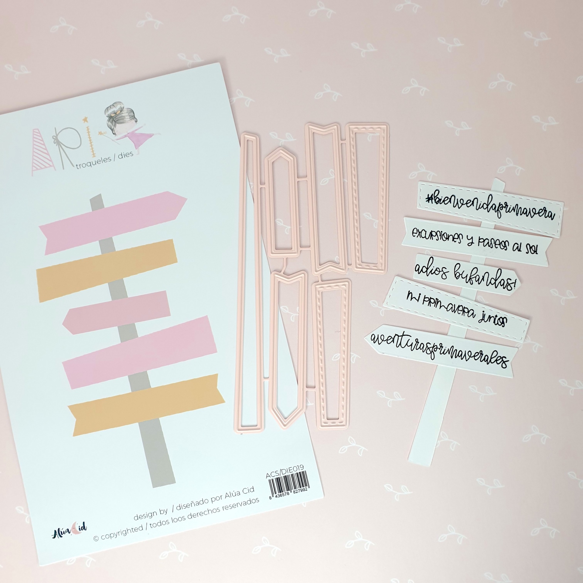 Kit de scrapbooking com papel de setas coloridas e moldes metálicos cor de rosa sobre fundo rosa