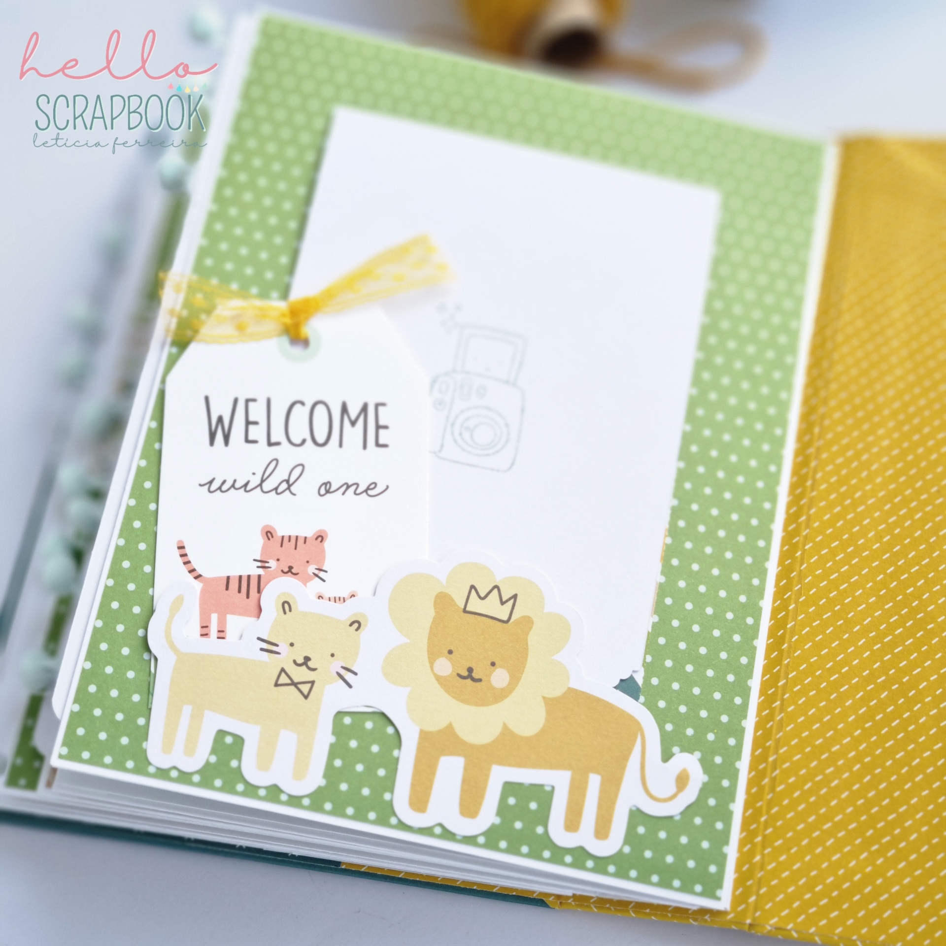 Livro de scrapbook com página decorada com animais e etiqueta 'WELCOME wild one'