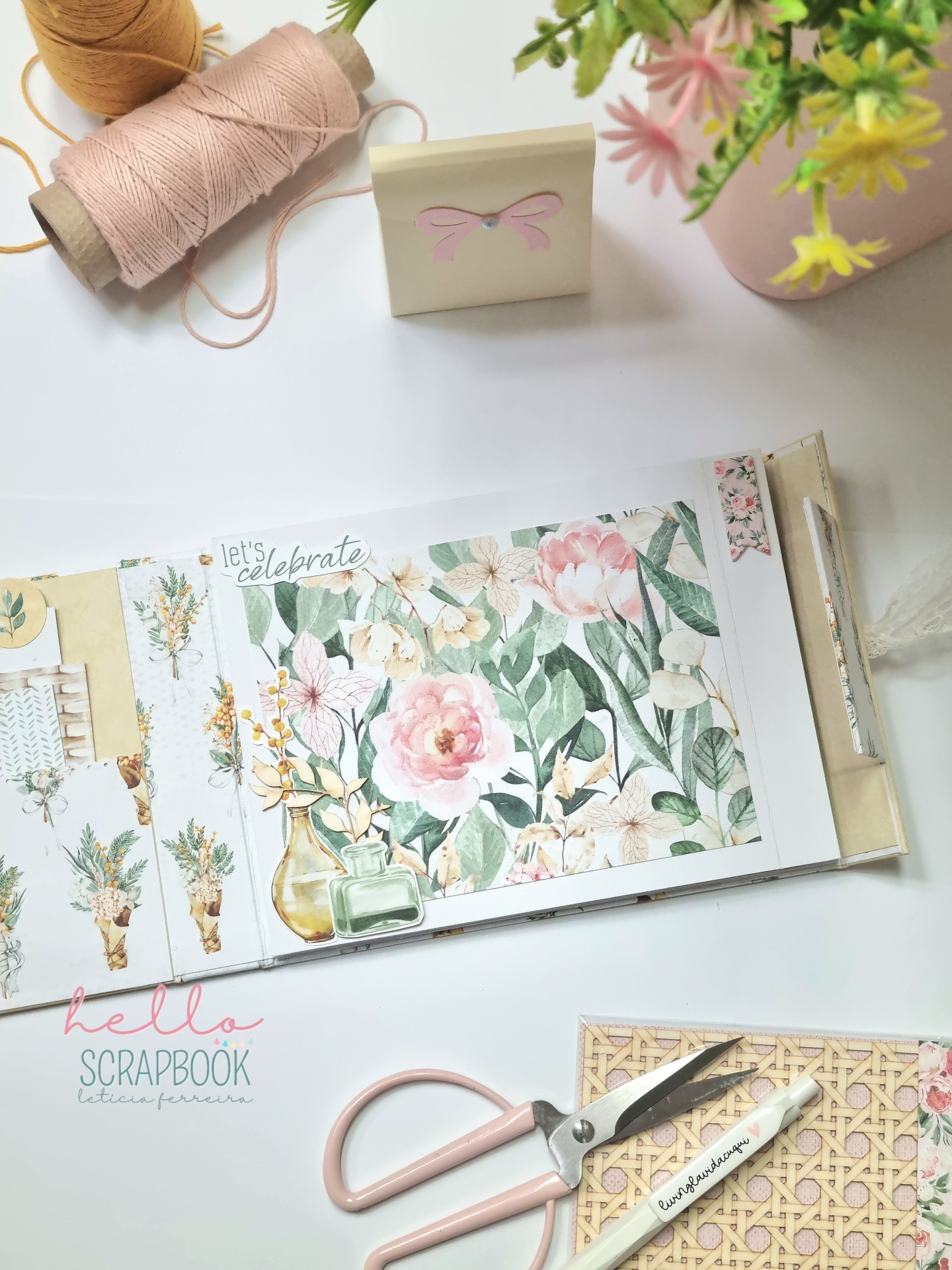 Papelaria para scrapbook com tema floral, tesoura rosa, linhas de costura e flores em fundo branco