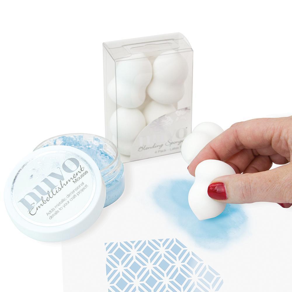 Recipiente com esponjas brancas, frasco de cristais mágicos e pó azul sobre papel com padrão geométrico azul.