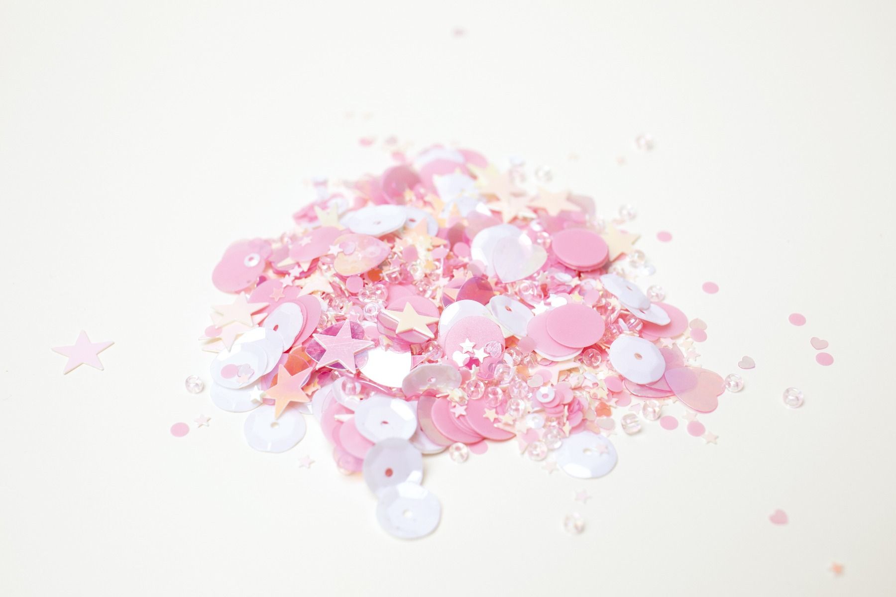 Lantejoulas coloridas rosa, branco e salmão em fundo branco