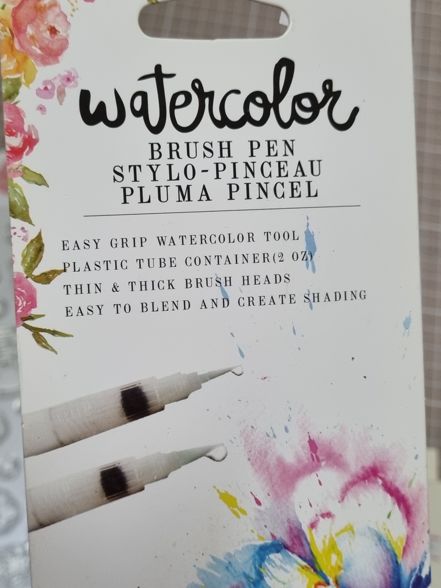 Embalagem de brush pen para aquarela com texto em várias línguas e detalhes florais coloridos.