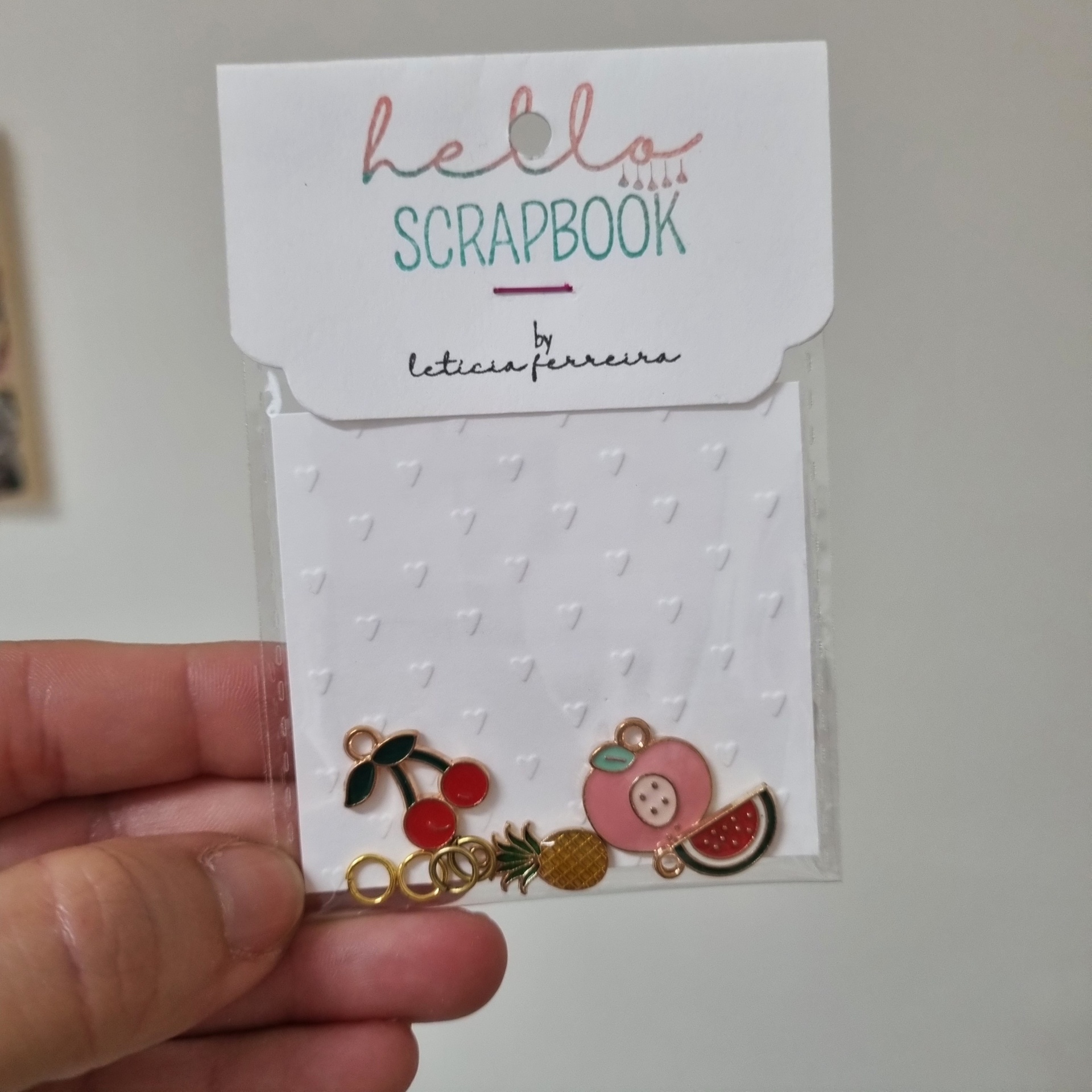 Conjunto de pequenos pendentes coloridos de metal esmaltado com formas de frutas e embalagem com texto