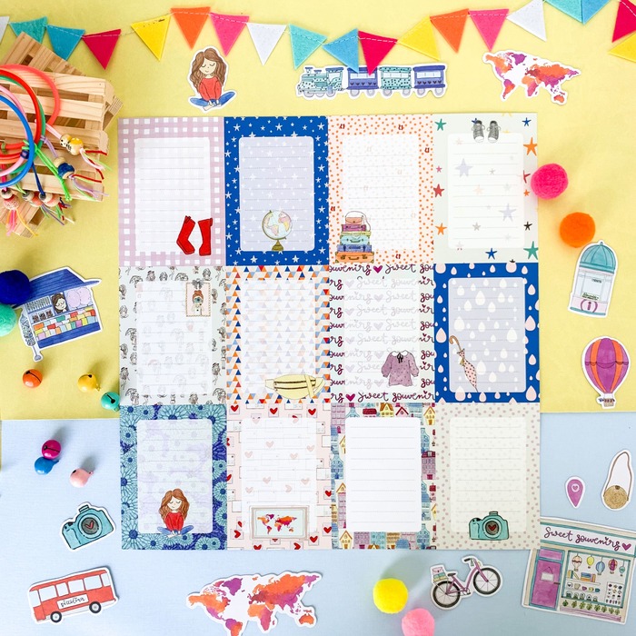 Folhas de papel decoradas com desenhos variados sobre fundo amarelo e azul com pompons e bandeirolas coloridas