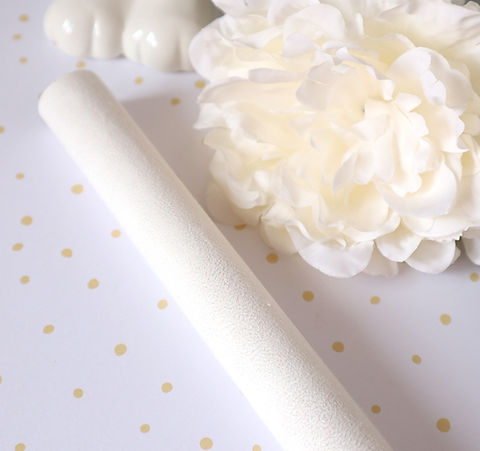 Vara branca texturizada junto a flor artificial branca sobre fundo branco com pontos dourados