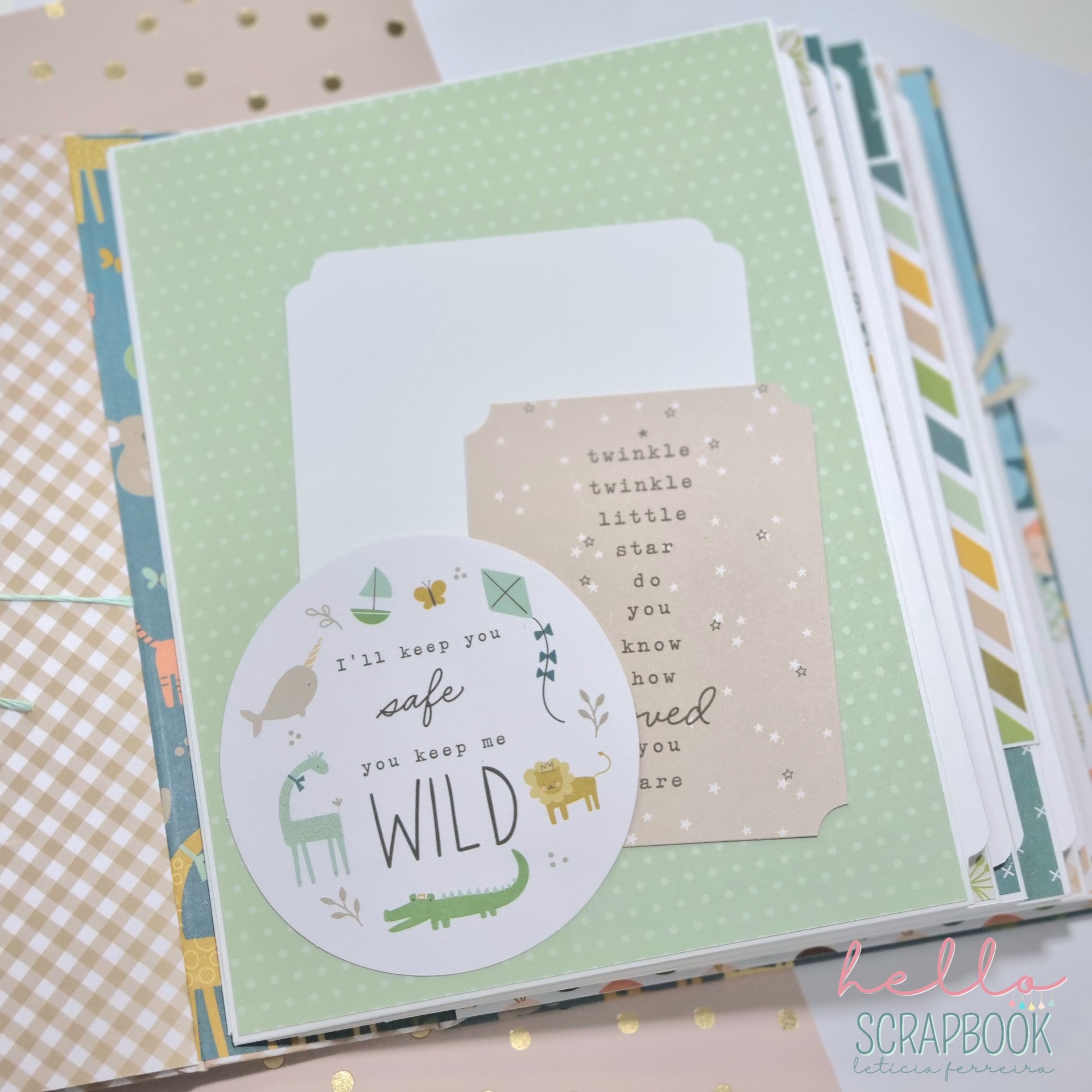 Página de livro scrapbook decorada com papel verde, etiquetas brancas e bege, desenhos de animais e texto, em superfície com estrelas brilhantes