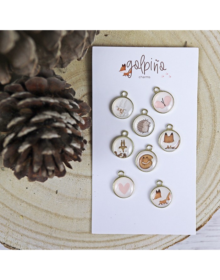 Conjunto de pendentes redondos com ilustrações de animais e corações em cartão branco sobre madeira clara