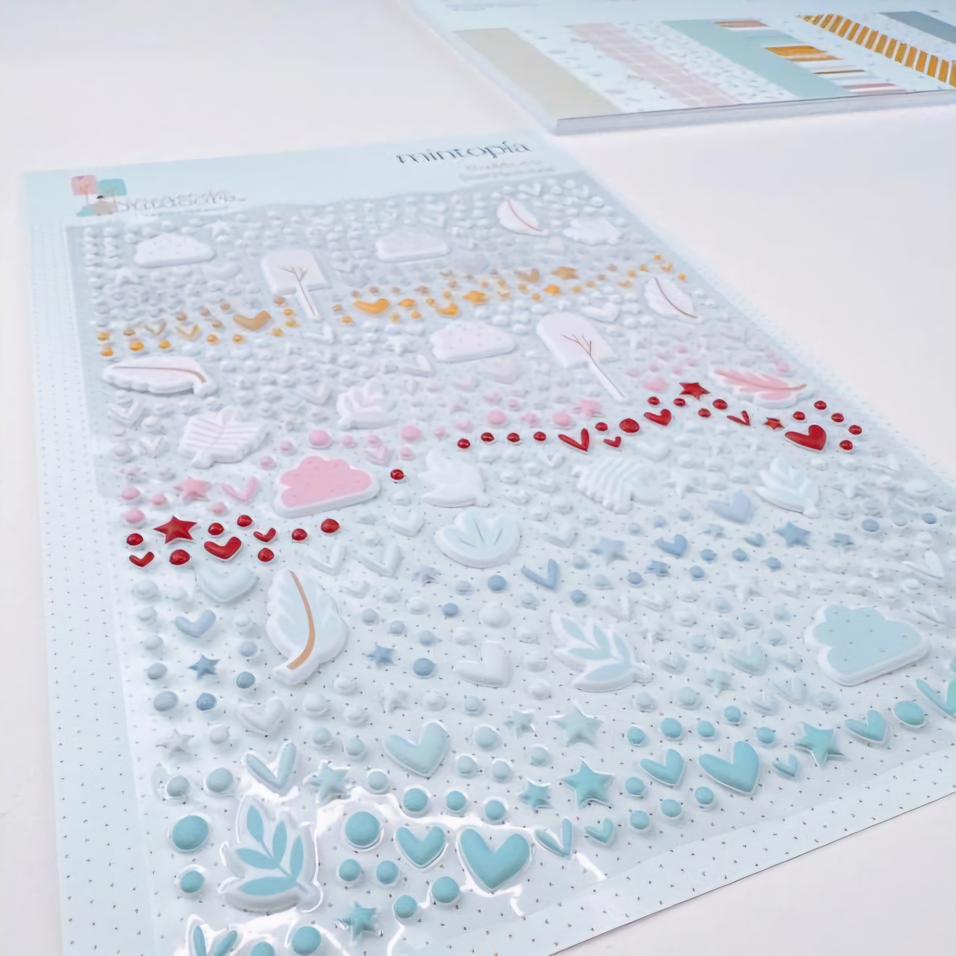 Folha de autocolantes em várias cores pastel com desenhos pequenos variados e papel com gráficos ao fundo